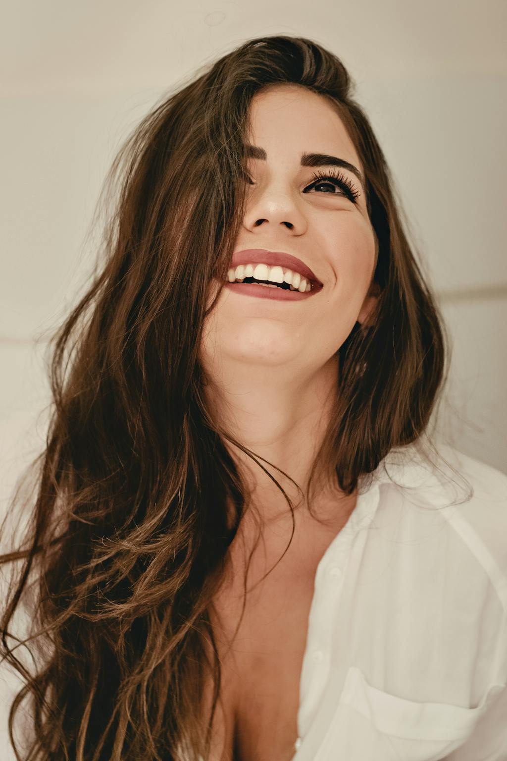 Portrait of a happy woman with long brunette hair and elegant style, expressing joy.