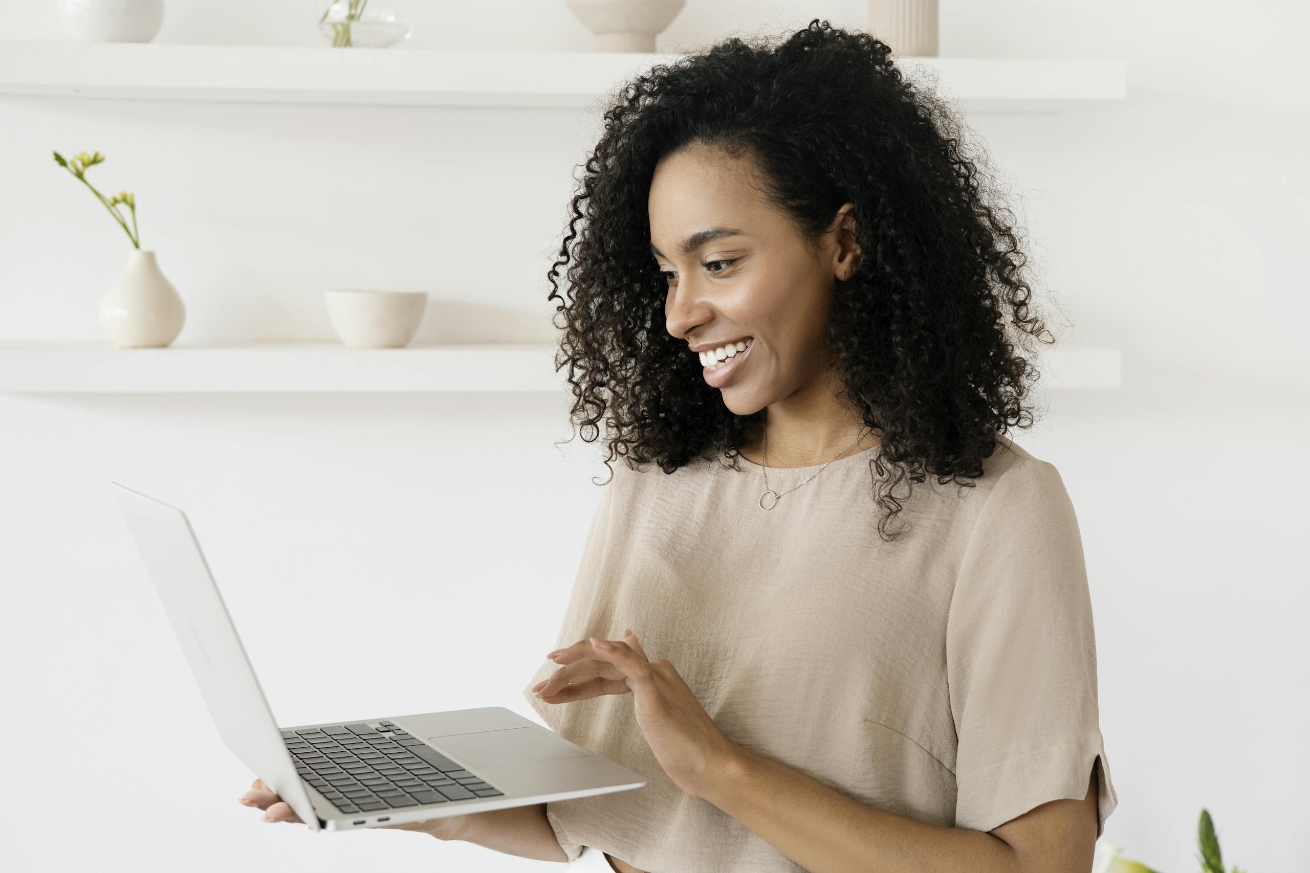 Smiling woman working on a laptop in a modern home office, highlighting freelance lifestyle.